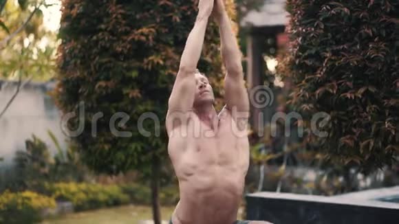 肌肉发达的男人在花园里做瑜伽运动视频的预览图