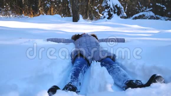无法辨认的年轻女孩躺在雪地草地上做天使快乐的女人在雪地里玩享受冬天的时光视频的预览图