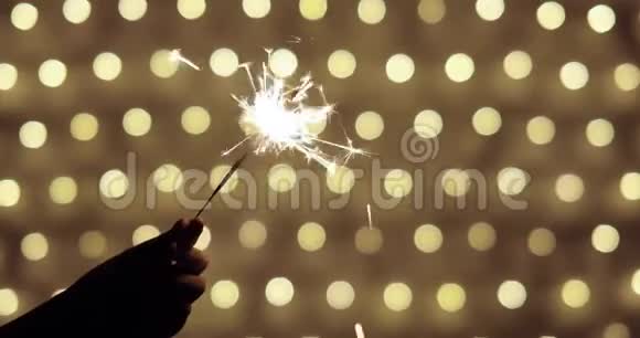 女孩的手拿着燃烧的火花在金色的背景与点在圣诞节视频的预览图