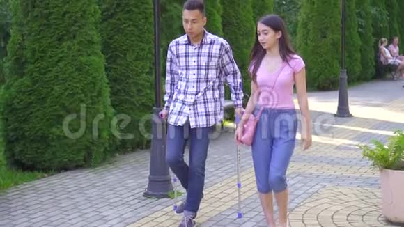 拄着拐杖断腿的亚洲青年男子与朴慢莫的亚洲青年女子交流视频的预览图
