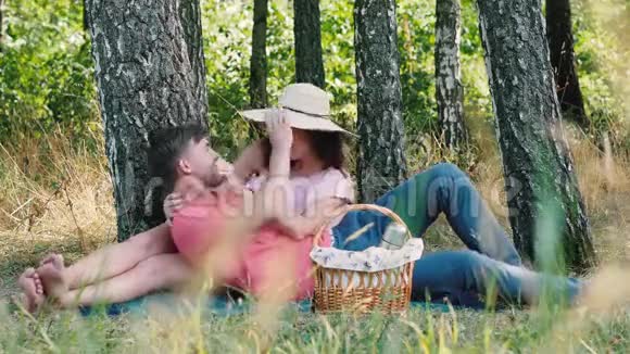 野餐时间快乐的年轻夫妇玩得很开心男人趴在她的手上公园的户外活动视频的预览图