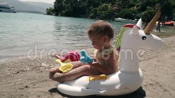 彩虹麒麟玩具和宝宝在海滩上暑假去海边希腊视频的预览图