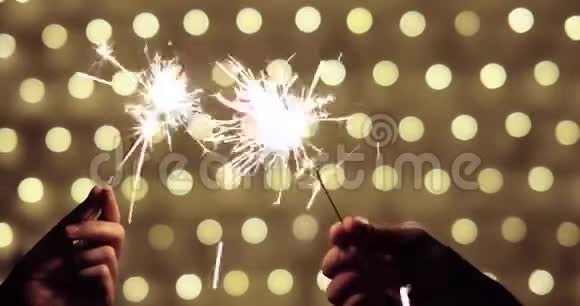 圣诞前夜一对夫妇手捧着燃烧的火花在金色的背景上视频的预览图