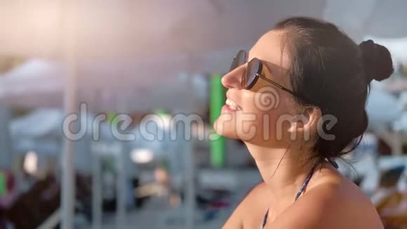微笑晒黑的年轻旅游女性在暑假享受日光浴中等特写视频的预览图