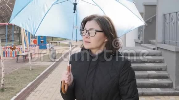 成熟的微笑着走着的女人穿着外套戴着带伞的眼镜视频的预览图