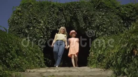 迷人的金发母亲和女儿一起在夏天的花园或公园里牵手散步家庭幸福妈妈和女儿视频的预览图