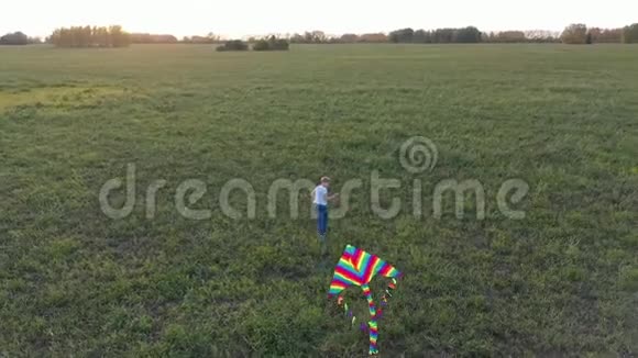 那个男孩在绿色的田野上带着风筝跑步欢声笑语喜庆的心情秋天日落视频的预览图