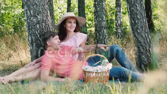 野餐时间快乐的年轻夫妇坐在户外微笑他把手伸向朋友他们开始挥手视频的预览图