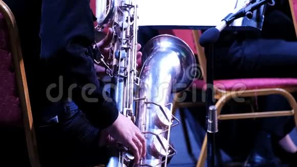 一个爵士乐队中萨克斯管上穿黑色西装的男人后景特写镜头铜管乐队的音乐家节日视频的预览图