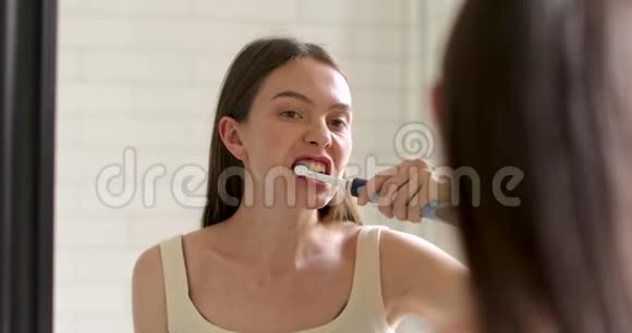 美丽的女人刷牙照镜子视频的预览图