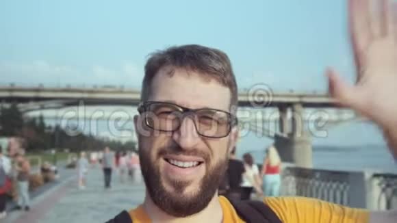 带着眼镜和胡子的快乐男性博客作者在街上对着镜头说话视频的预览图