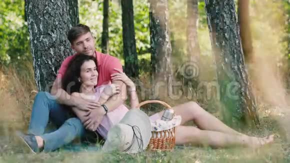 野餐时间快乐的年轻夫妇玩得很开心那个男人拥抱他的女朋友抚摸她的手公园的户外活动视频的预览图