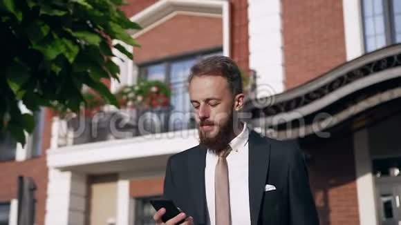 年轻英俊成功的商人穿着正式西装走路时打着手机打着领带视频的预览图