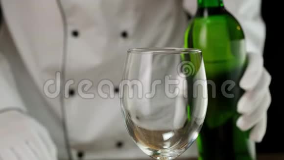 白葡萄酒从瓶子里倒入黑色背景下的玻璃中快关门视频的预览图