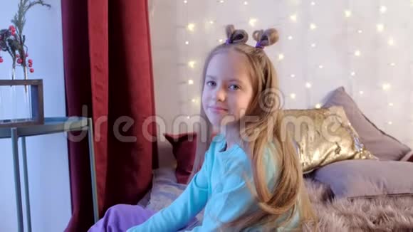 女孩坐在床上看着相机在卧室装饰的花环圣诞视频的预览图