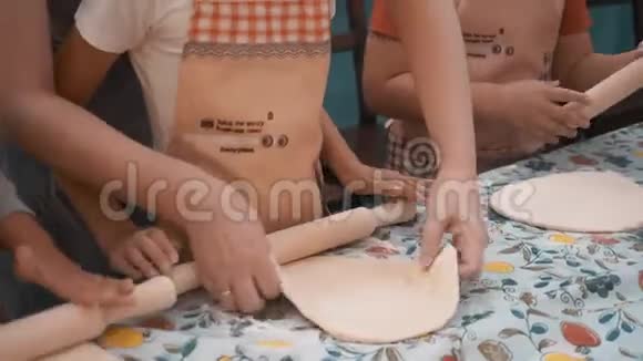 女厨师教女孩在学校的烹饪课上用木辊滚面团孩子们准备面团视频的预览图