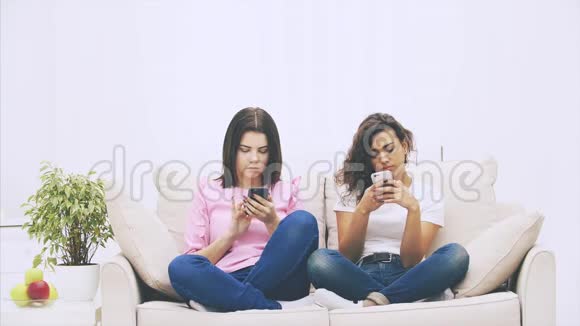 美丽的年轻古怪的美国黑人和黑发白种人女孩坐在沙发上的洛托斯位置电话视频的预览图