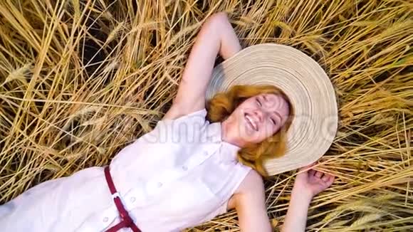 在摄像机的上方旋转着躺在麦田里笑着的女人视频的预览图