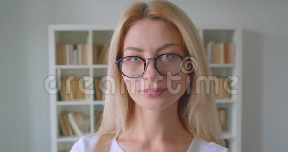 照片中的白种人成年金发女性戴着眼镜看着镜头在图书馆的室内开心地笑着视频的预览图