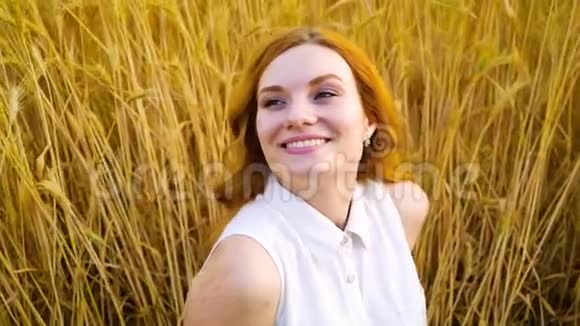 幸福的红发女人坐在麦田里仰望天空的肖像视频的预览图
