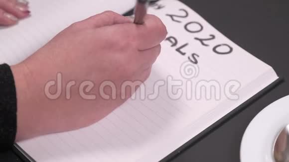 特写女人手写目标列表深色桌子上的笔记本视频的预览图
