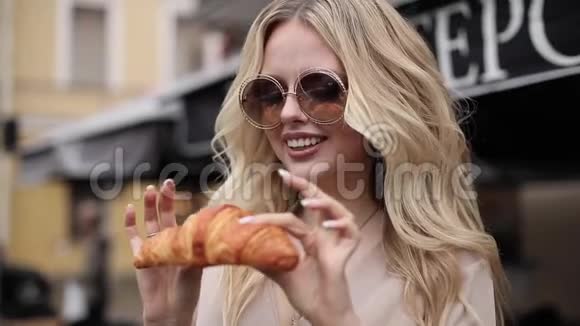 戴墨镜的漂亮女孩吃羊角面包视频的预览图