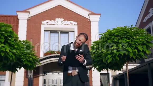 一个英俊的成功男人留着胡子穿着商务服装打着领带站在商务办公中心附近视频的预览图