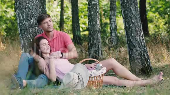 野餐时间快乐的年轻夫妇在公园里放松那个男人拥抱他的女朋友指着他的手快乐的未来视频的预览图