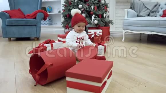 可爱的小男孩穿着新年的衣服戴着筒子帽从盒子里拿着盖子坐在背景上视频的预览图