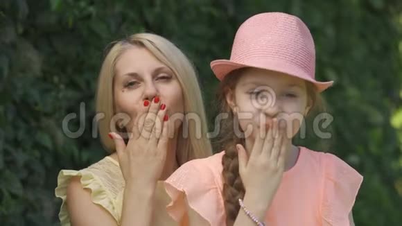金发母亲和她的小女儿在坐着的时候用空气亲吻镜头视频的预览图