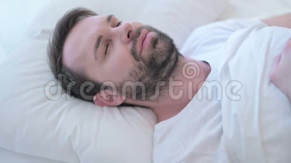 睡觉的大胡子床上颈部疼痛的年轻人视频的预览图