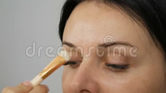 一种特殊的刷子在模特的眼皮上涂上粉底霜然后再开始化妆眼睛和女人的脸视频的预览图