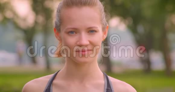 城市公园里年轻漂亮的运动型女慢跑者看着镜头开心地笑着的特写镜头视频的预览图
