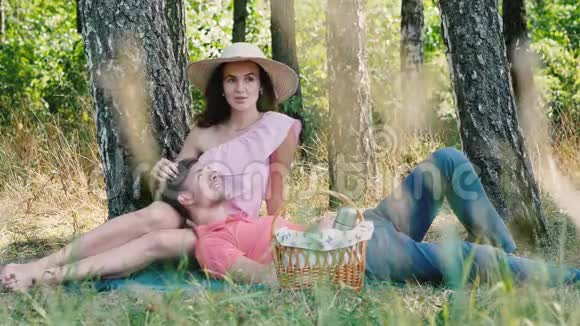 野餐时间快乐的年轻夫妇坐在户外微笑男人趴在她的手上公园的户外活动视频的预览图