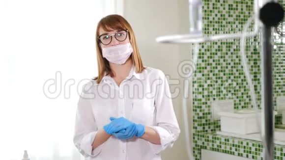 美丽的女医生戴着无菌口罩看着相机的肖像女人用蓝色擦手视频的预览图