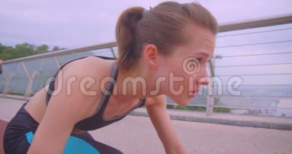 特写侧景照片年轻可爱的白种人运动女性慢跑者坐在一个开始的位置并在跑步视频的预览图