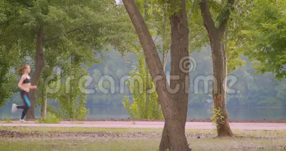 城市公园户外慢跑的年轻漂亮运动的女跑步者特写侧景肖像视频的预览图