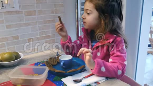 四岁的女孩在家里的小厨房里吃早餐里面有牛奶和饼干视频的预览图