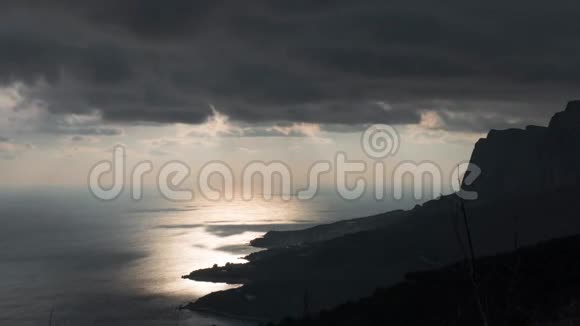 日落时分在岩石海岸附近的海面上有着太阳的暗云视频的预览图