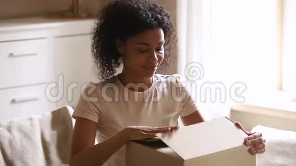 快乐的非洲妇女顾客收到纸板箱打开的包裹视频的预览图