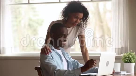 快乐的黑人丈夫展示微笑的妻子有趣的笔记本电脑视频视频的预览图