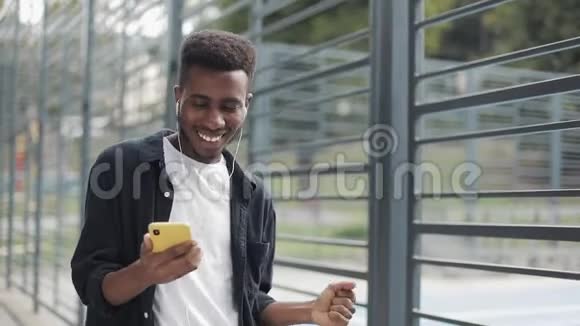快乐的非洲男人用耳机听音乐视频的预览图