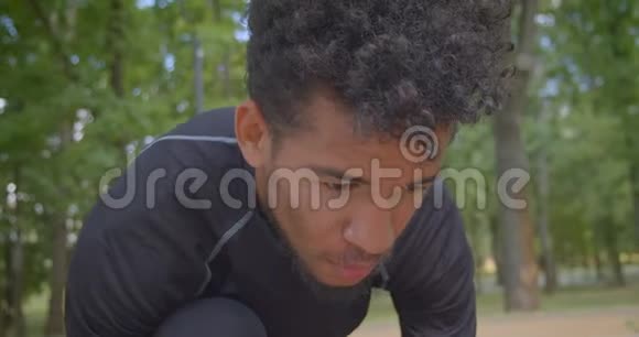 年轻强壮的非洲裔美国男性慢跑者准备在户外公园跑步的特写镜头视频的预览图