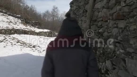 一个女孩走在雪地里的小屋里触摸着它的墙壁视频的预览图