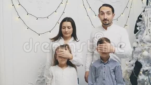 父母用手捂住孩子眼睛仿佛在给圣诞节带来惊喜但却表示没有钱买视频的预览图