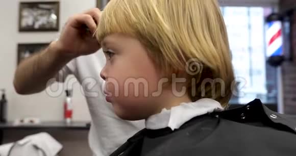 可爱的金发孩子坐在理发店视频的预览图