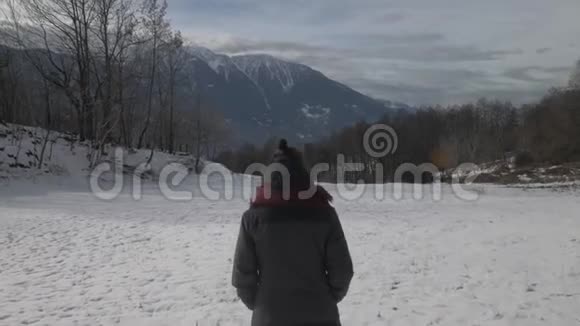 女孩走在雪山的冬季景观中稳定下来视频的预览图