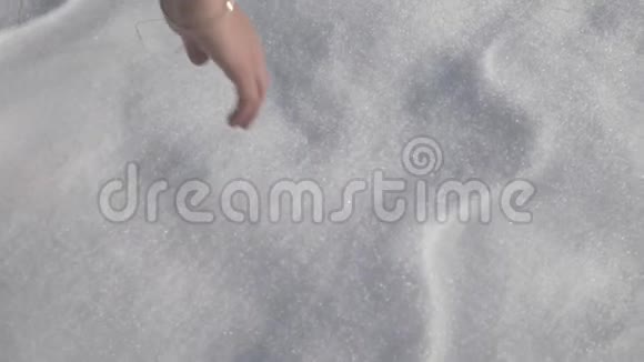 女孩用手触摸和抓雪近距离射击视频的预览图