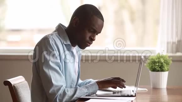 一个精力充沛手提电脑文件的黑人坐在办公桌前视频的预览图
