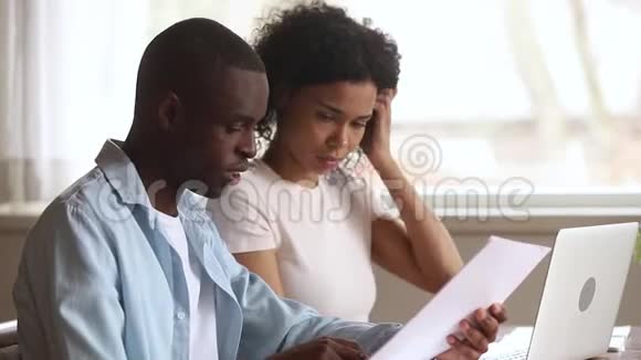 做文书工作的认真的非裔美国人夫妇一起使用笔记本电脑视频的预览图